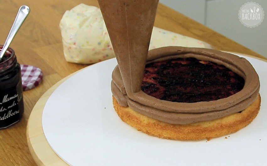 Konfetti Drip Cake: Schokoladencreme am Bodenrand aufspritzen
